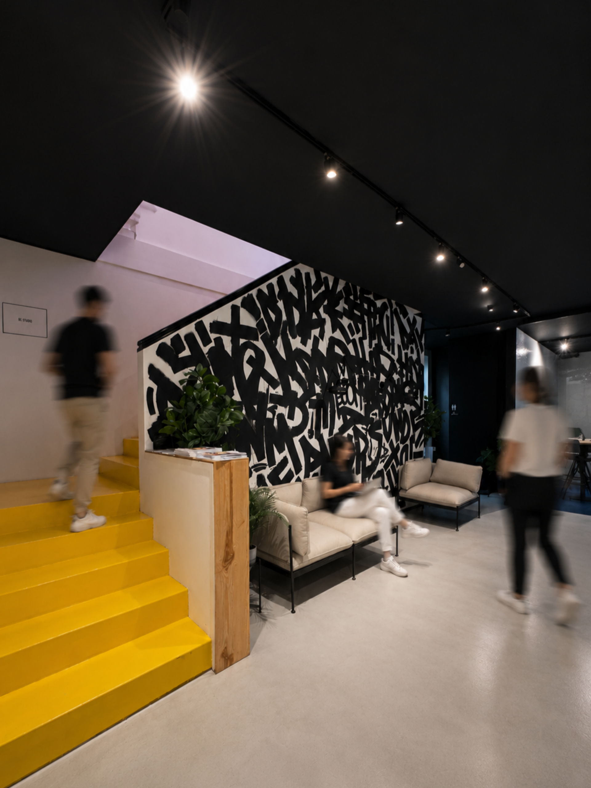 Bright yellow staircase next to a bold graffiti mural with a lounge area