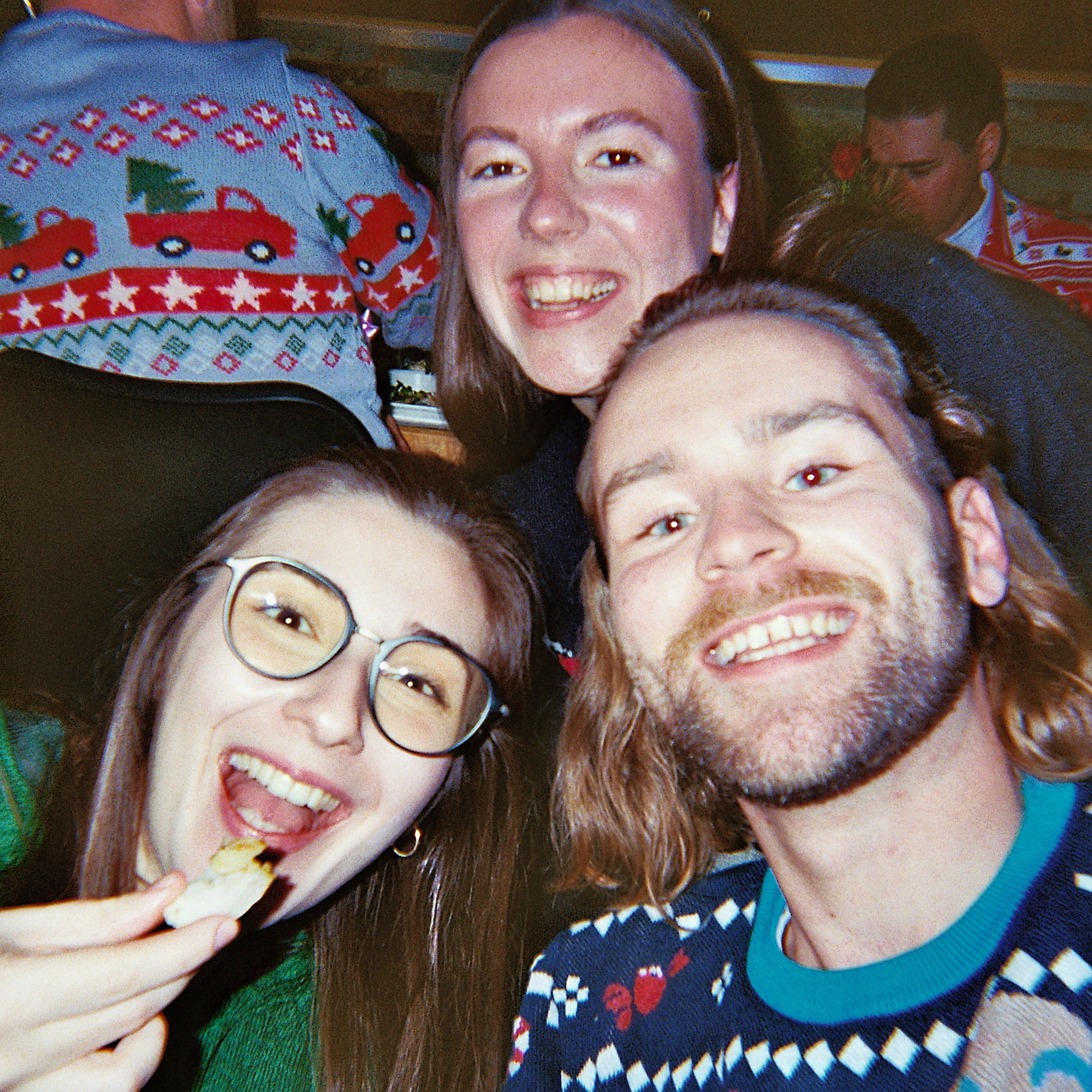 Three colleagues laughing in Christmas sweaters at the office party