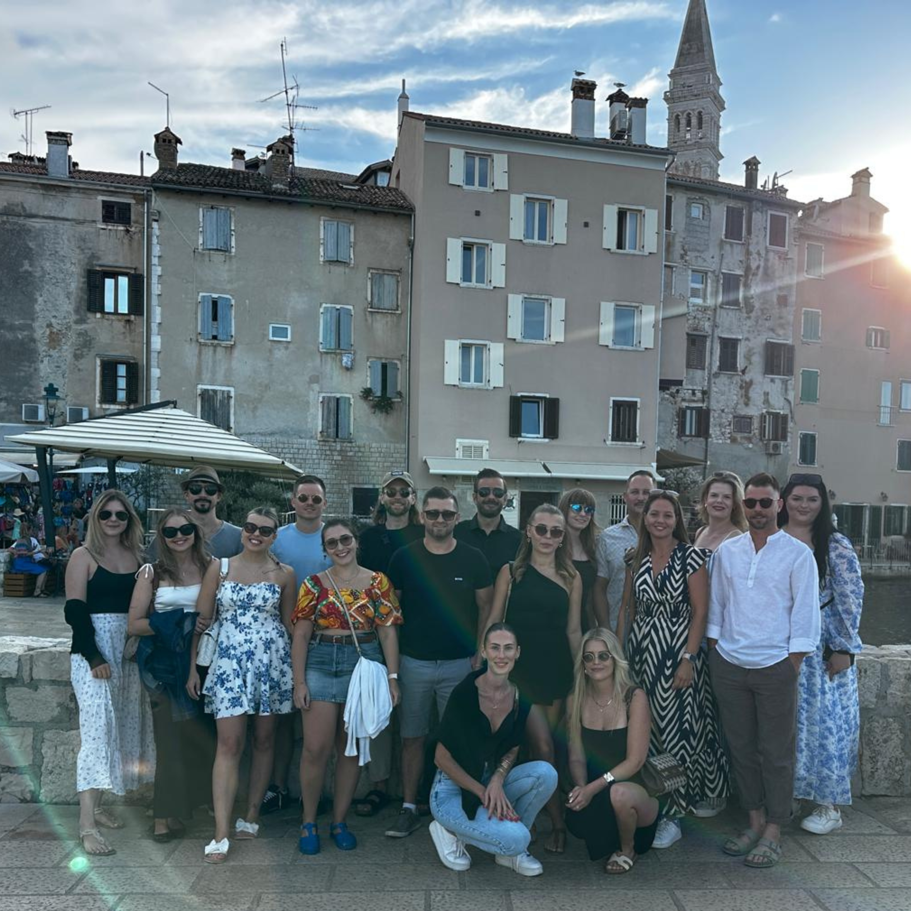 The team gathered in front of colourful Mediterranean buildings at sunset